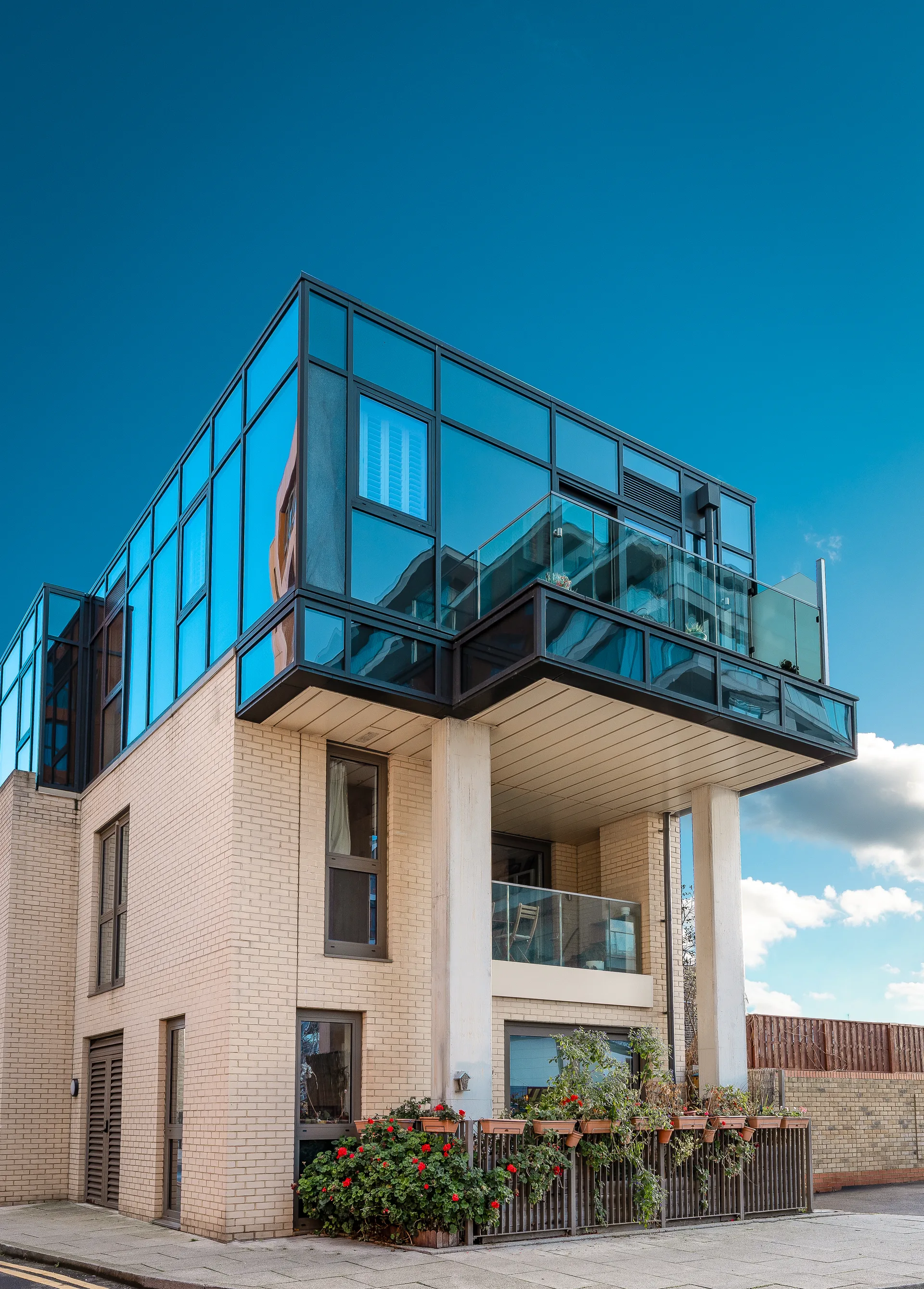 Angle View Of A Contemporary Brick Apartment Building Featuring Extensive Floor To Ceiling Glass Windows And Balconies.